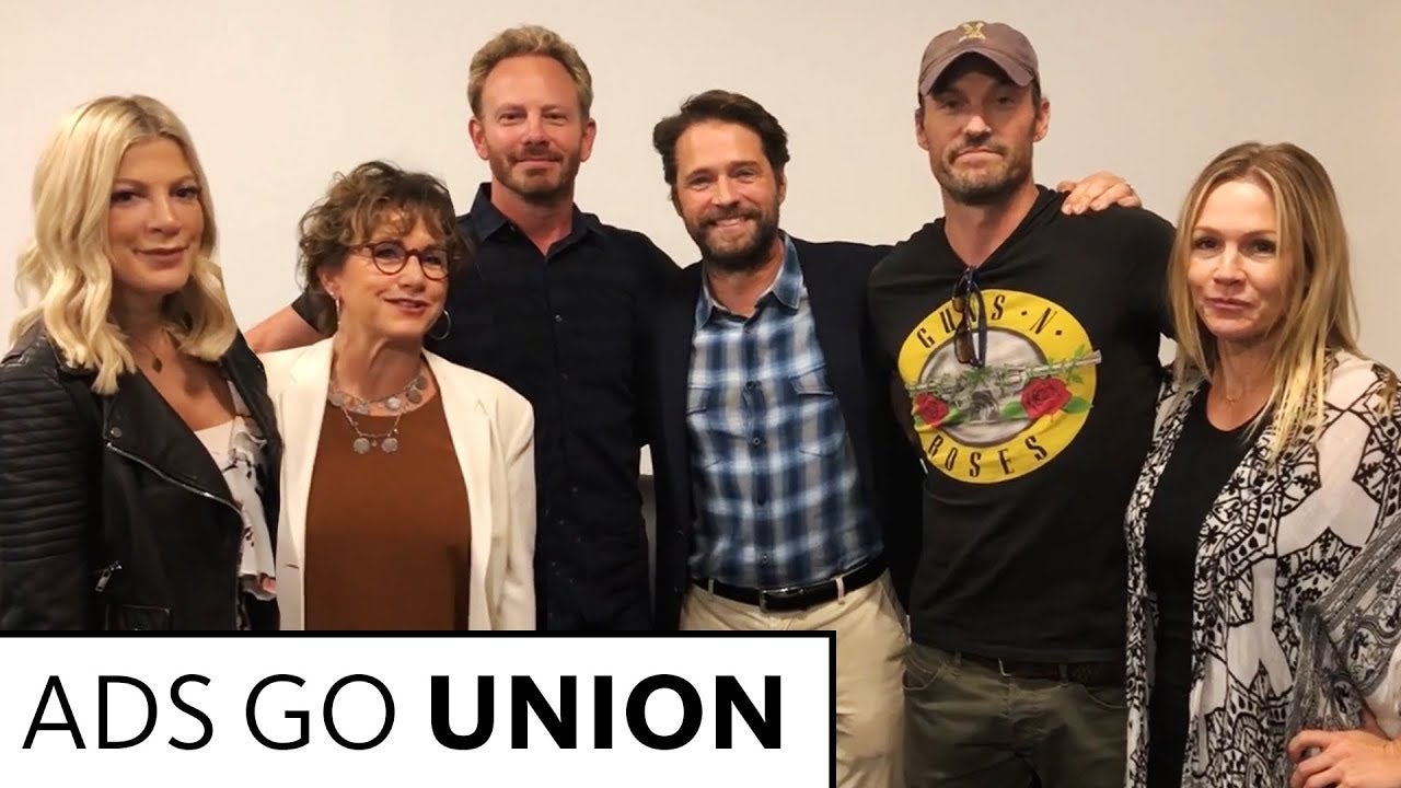 From L-R: Spelling in black leather jacket, Carteris in auburn blouse and white blazer, Ziering in black button up, Priestley in blue and white button up with dark jacket, Green in Guns and Roses t-shirt with baseball cap and Garth in black top and kimono