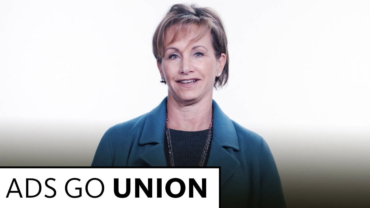 Carteris in dark top with blue coat standing in front of white background