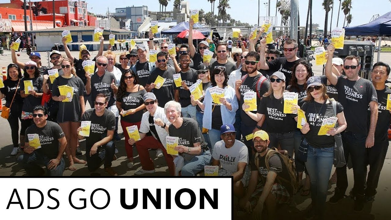 Large group of people in four rows holding yellow and white leaflets