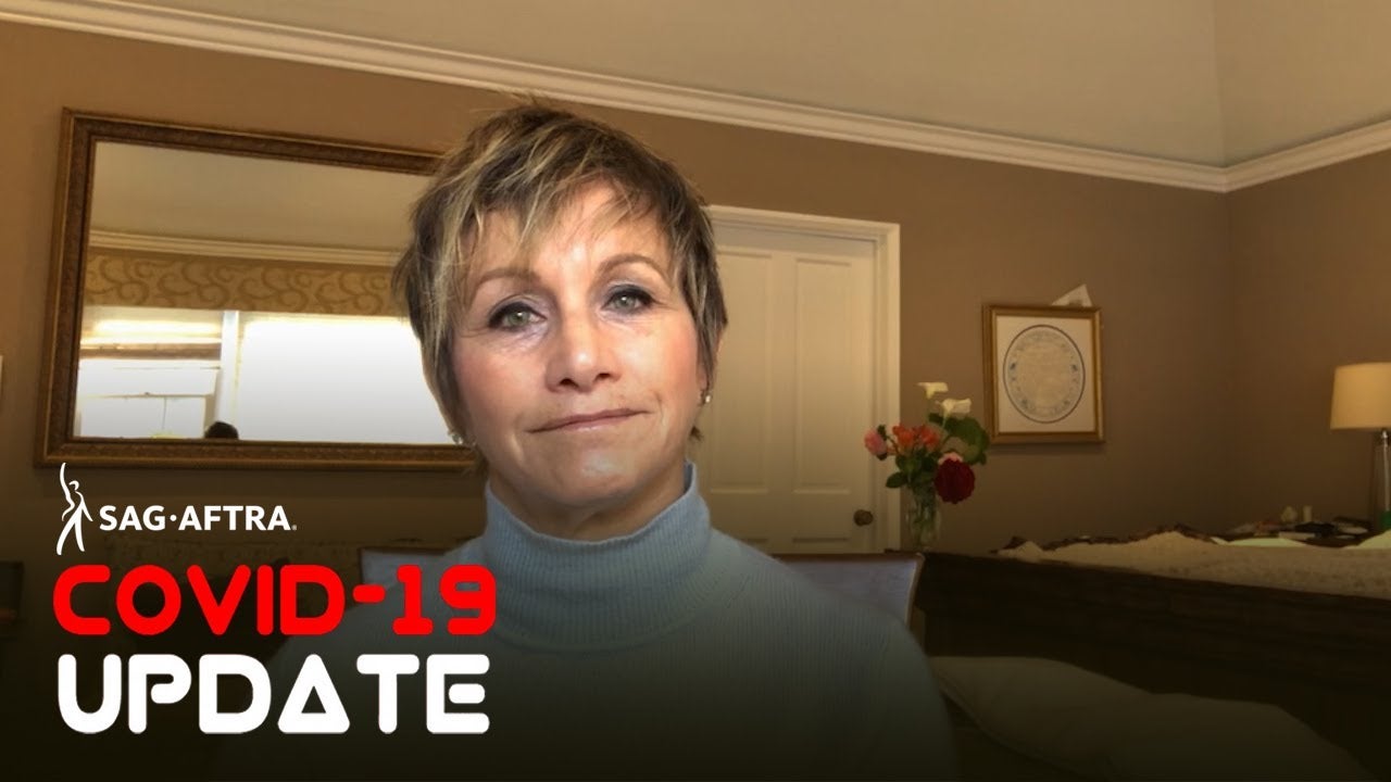 Carteris in blue turtle neck looking at camera with bedroom background. 