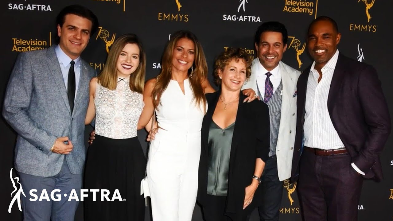 Group of members standing shoulder to shoulder with SAG-AFTRA and Emmy step and repeat in background
