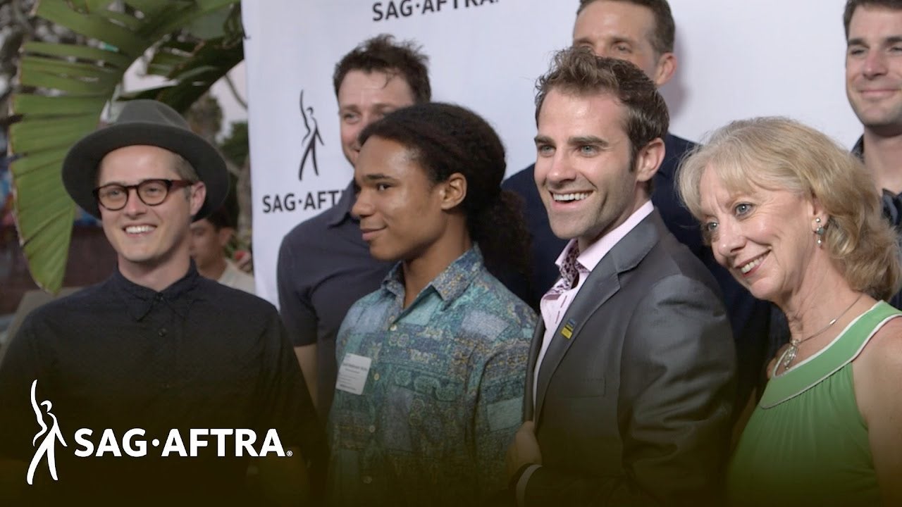 SAG-AFTRA members standing in front of a step and repeat smiling at camera