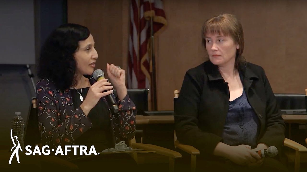 Sallak-Williams on left speaking into Mike with panelist on her left looking at her.