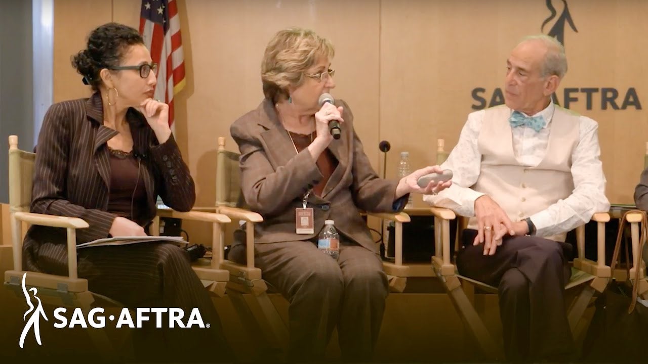 Panelists looking at panelist on right while middle panelist speaks into mic