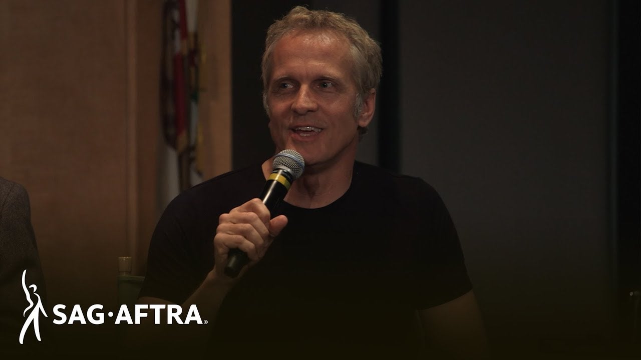 Fabian in black t-shirt holding mic in right hand looking off to his right