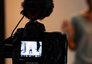 An image of a camera filming a performer.