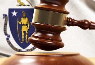 Image of a gavel with the Massachusetts Flag in the background.