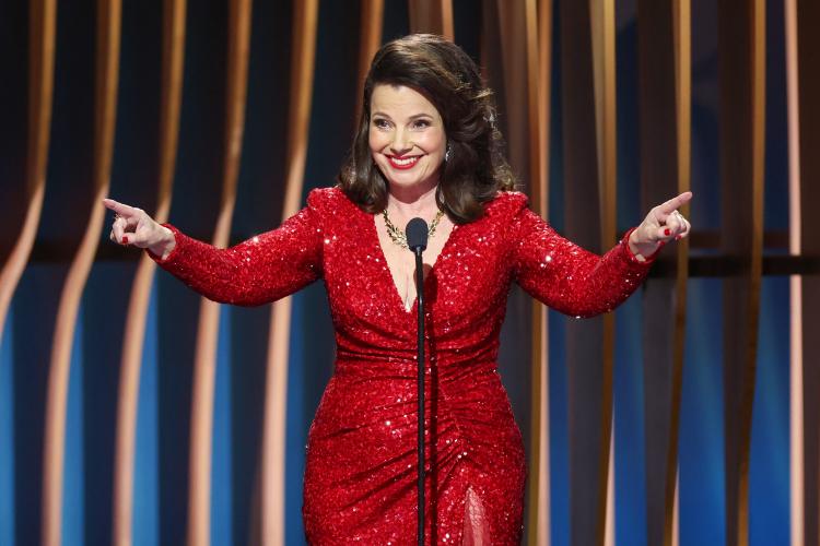 Drescher wears a red sequined dress. Smiling towards the crowd, her arms are outstretched.