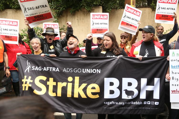 Members holding a banner "#StrikeBBH" and posters "Unfair. SAG-AFTRA on strike against BBH Ad Agency"
