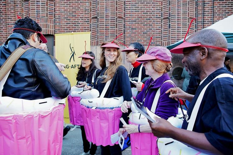 members wear a red visor with a red pipe cleaner on their head to look like a cherry. Around their hips is a cupcake costume in a pink wrapper and white frosting with sprinkles held up by white suspenders