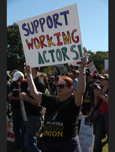 Supporter holding "SUPPORT WORKING ACTORS" poster wearing a black SAG-AFTRA #AdsGoUnion t-shirt.