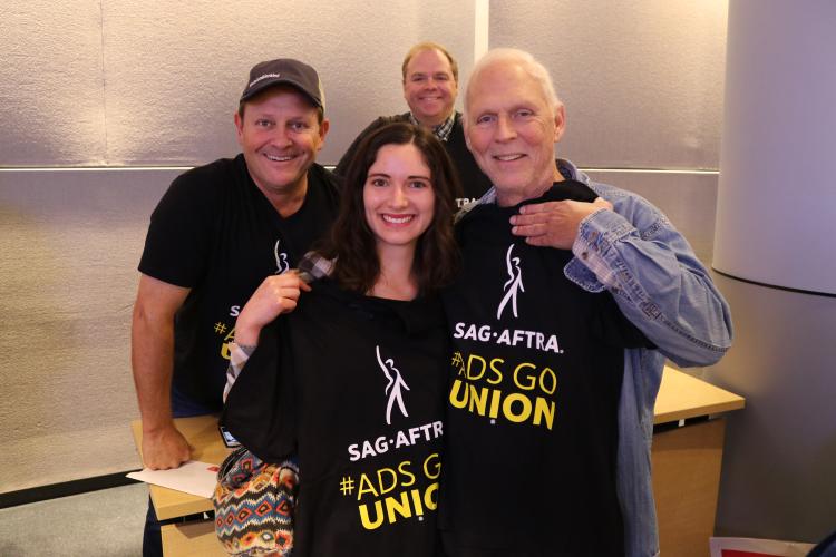 Members holding up their black SAG-AFTRA #AdsGoUnion shirts in the James Cagney boardroom 