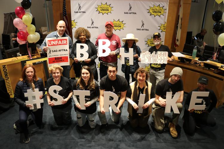 Members holding individual letters of "#StrikeBBH" in front of a SAG-AFTRA #AdsGoUnion back drop