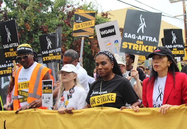 SAG-AFTRA leaders lead the march holding a SAG-AFTRA banner.