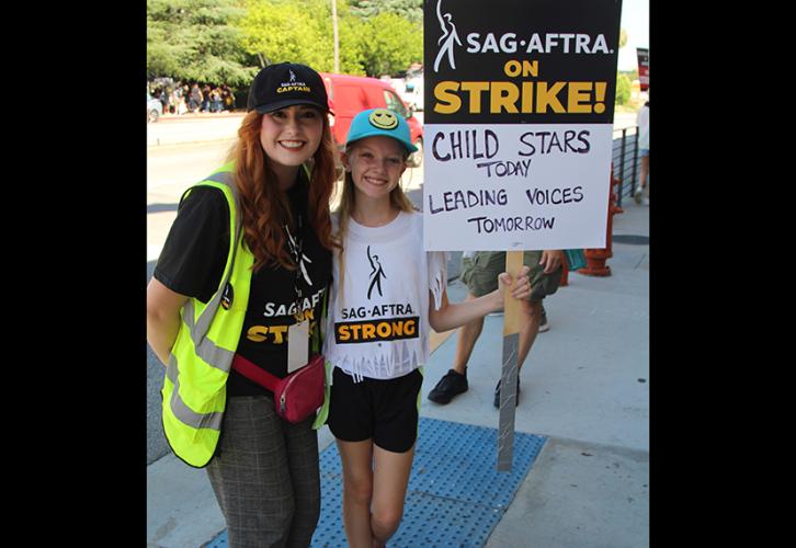 Strike captain Jillian Clare poses with SAG-AFTRA L.A. Local member Ellie Grace Pomeroy, who is holding a picket sign.
