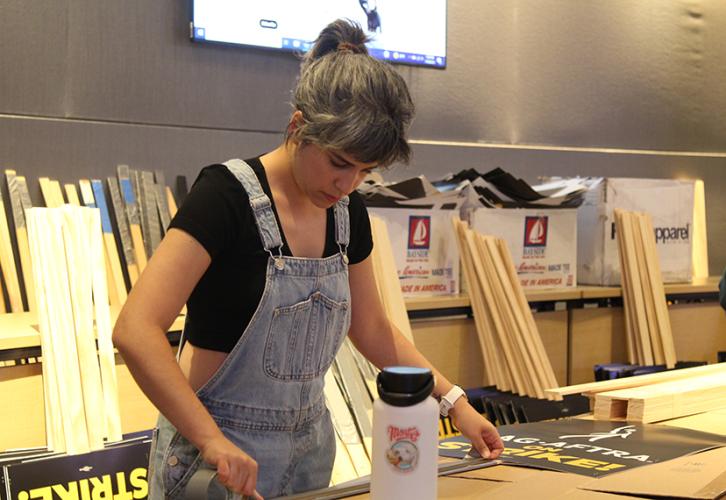 A member, surrounded by supplies, builds a sign.