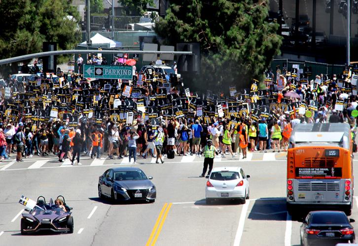 Thousands of picketers flood the streets at the inaugural Universal picket on Aug. 4 while cars drive by.