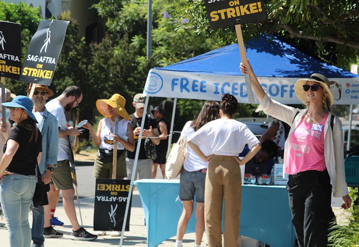 People picket, while a nearby coffee stand offers beverages to strikers.
