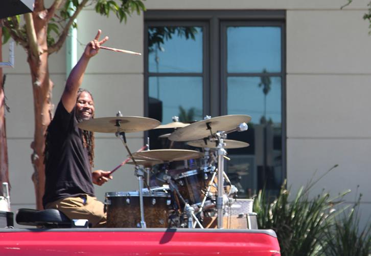 #SherriffDrumman plays the drums on a sidewalk.