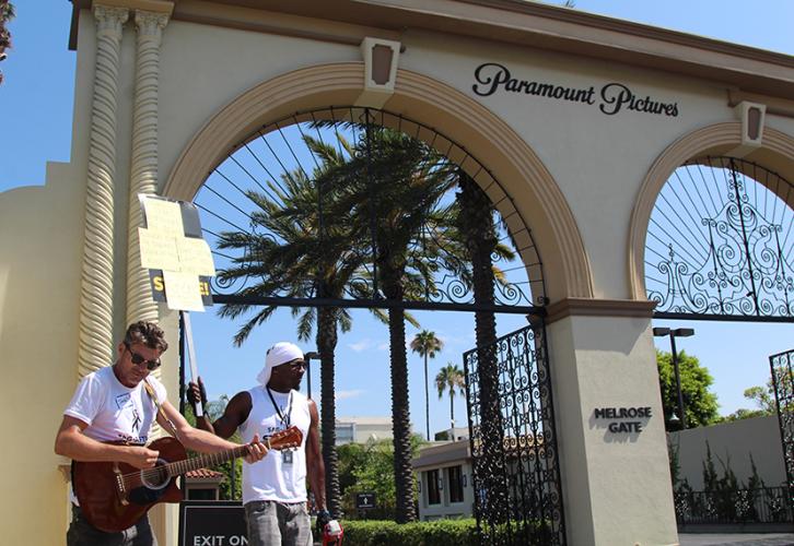 Members sing in front of the Paramount Pictures gate.
