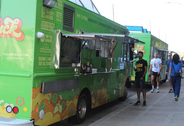 A green food truck is parked next to a curb.