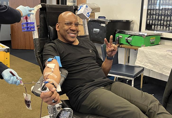 Knight flashes a V-for-victory sign as he sits in a chair getting his blood drawn.