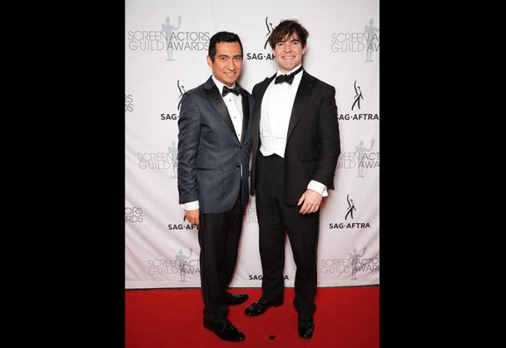 Two men smile on the red carpet.