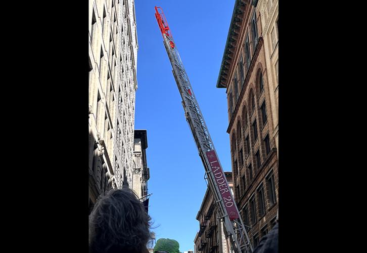 A Fire truck ladder is raised several stories.
