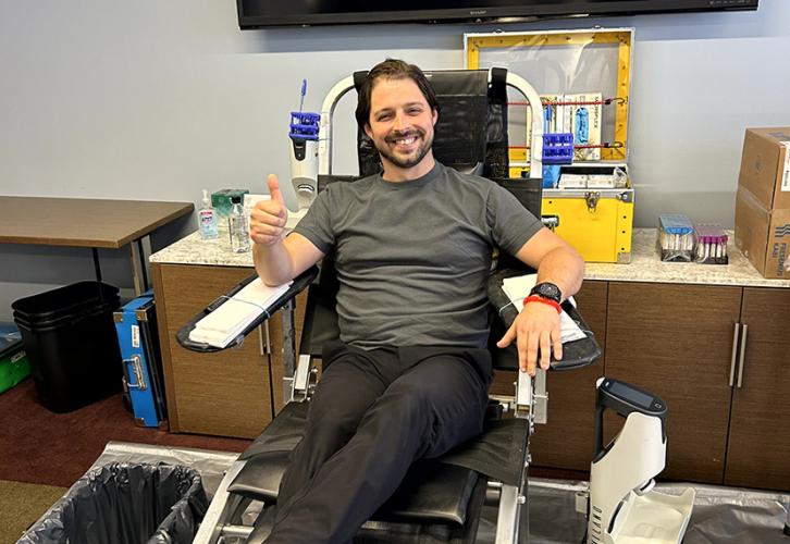 A man gives a thumbs up as he prepares to give blood. 