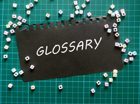 'GLOSSARY' in white text on black matte paper on a green cutting board