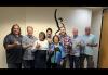 From left, Shawn Christensen,Scott Swartz, Mericia Palma Elmore, Charles Uyehara, Mazie Hirono, John Leblanc, Noah Evlsin, and Christopher Weicking. Eight people, throwing shakas, stand in front of a mural depicting the SAG-AFTRA logo. There are five white men and one Hawaiian man in aloha shirts, and two women with short hair, front and center.