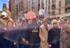 From left, Jack Mulcahy, Rebecca Damon, Eugene Calamari, Avis Boone, Ezra Knight, Linda Powell, Samatha Mathis, and Josh Evans The group, wearing warm-weather jackets, pose for a picture on the street. Shirts on poles can be seen in the background.
