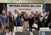 A group poses against a banner that says Nevada State AFL-CIO - Union Strong. There are flags on either side.