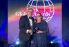 SAG-AFTRA Chief Communications & Marketing Officer Pamela Greenwalt, right, accepts the 2024 PRWeek Global Awards’ Issues and Crisis Campaign of the Year award on May 15. Photo courtesy of PRWeek. Greenwalt, right, stands with a taller gentleman. Together they hold the award statuette, which appears as two grid outlines of the world. Behind them is a PRWeek Global Awards step-and-repeat backdrop.