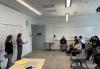 SF-NC Local Assistant Executive Director Dee Dee Escobedo, left, and Broadcast Manager Lea Hausherr speak to SF-NC Local member Elaine Leung’s BECA students at San Francisco State University on May 8. Photo by Elaine Leung. Escobedo, left, and Hausherr speak to college students in a classroom. Both women are in front of a whiteboard on the far left; the students are in desks on the far right. As Hausherr speaks, she gestures with her hands.