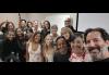Oahu scene study participants pose for a selfie after a series of classes. A group of diverse actors pose for a selfie in a classroom. There's an American flag in the background.