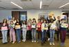 From left, SAG-AFTRA members Lena Marano, Onie Watlington, New York Young Performers Committee member Rachel Resheff, Audrey Simone Winters, Ivy Johnson-Tejada, Lily Lewinter, Isabella Mia, Zachary Cruz, New York Local President Ezra Knight, Ethan Rodriguez, Mateo Castel, Naya Desi-Johnson, Jonathan O’Reilly and Zachary Golinger show off their artwork. A group of people stand in a row holding pieces of art they have made out of canvas and multicolored pieces of paper.