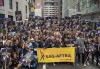 SAG-AFTRA members assemble on East 44th Street ahead of the 2024 New York City Labor Day Parade and March. Photo by Derek French | Shutterstock for SAG-AFTRA. A large group of SAG-AFTRA members are gathered on a street. They are wearing black T-shirts with white and yellow text that reads “SAG-AFTRA on Strike.” They hold signs that read “SAG-AFTRA Video Game Strike” in white and yellow text on a black and purple background with the image of a fist holding a video game controller. The people at the front of the group hold a SAG-AFTRA parade banner with black text on a yellow background.